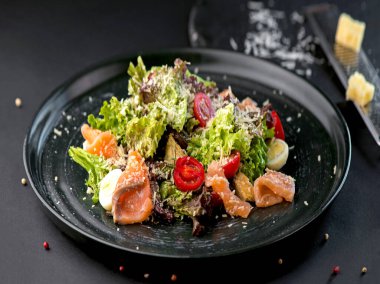 Somonlu sebze salatası ve koyu arkaplanda taze otlar. Yan görünüm, yakın plan.