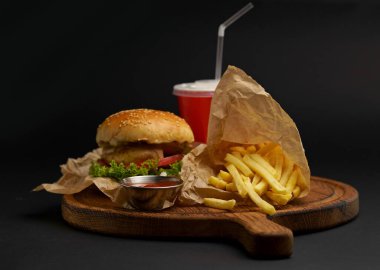 Homemade delicious double burger with beef, lettuce, bacon, tomato and cheese on a wooden background.