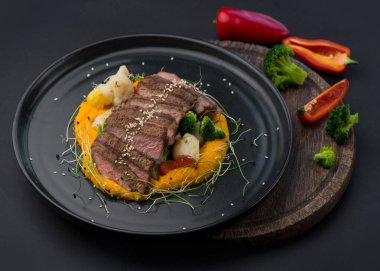 Slow-fired beef with pumpkin puree and vegetable salsa. Fried meat with vegetables on a dark