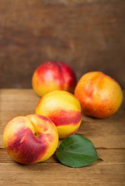 fresh nectarines with leaves on wooden background