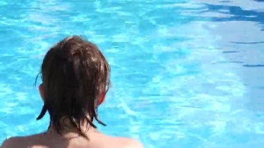 A teenager swims, dives in a pool in a private courtyard.