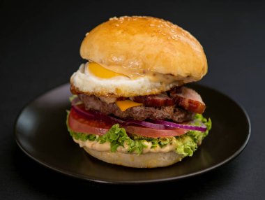 Big tasty burger with beef cutlet on a black background