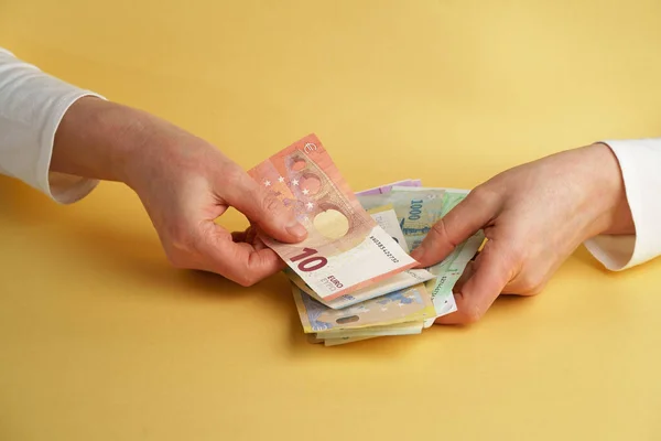 Euro Money. Female hands holding euro banknotes on a yellow background.