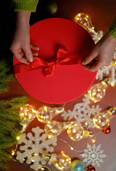 クリスマスの飾りと木製のテーブルの背景に置かれたクリスマスの贈り物を保持する女性 — ストック写真