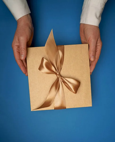 Auf Einem Blauen Flachen Hintergrund Halten Hände Ein Geschenk — Stockfoto
