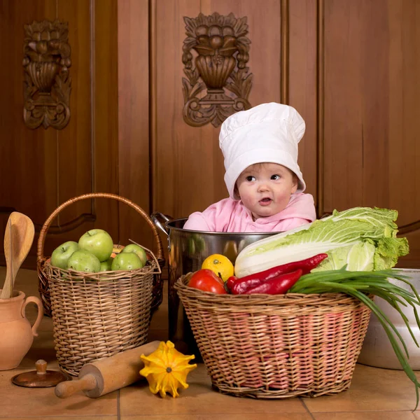 一个笑着的婴儿坐在一个大锅里的画像 锅里有蔬菜和食物 — 图库照片