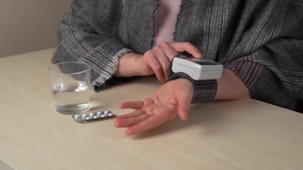 女性は健康を管理している 女性は自宅で電子的運動量計で血圧を測定し — ストック動画