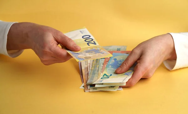 Female hands holding euro banknotes on a yellow background. Euro Money.
