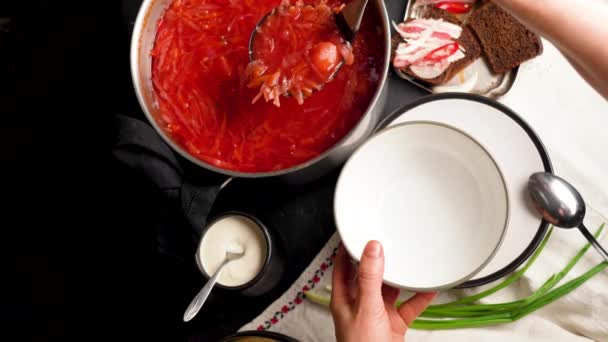 ボウルに白い豆と伝統的なウクライナのロシアのボルシチ 黒ラスティックテーブルの上に赤ビートのルートスープボルシュのプレート ビートルのスープトップビュー 伝統的なウクライナ料理 — ストック動画