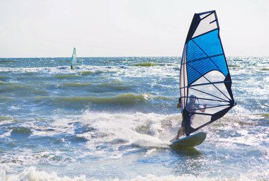 Young man surfing the wind on a bright summer day clipart