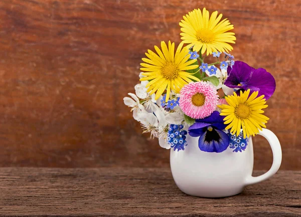 small spring bouquet. Bouquet of wild flowers in a small vase on a wooden table. Bouquet of daisies.