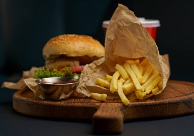 Homemade delicious double burger with beef, lettuce, bacon, tomato and cheese on a wooden background.