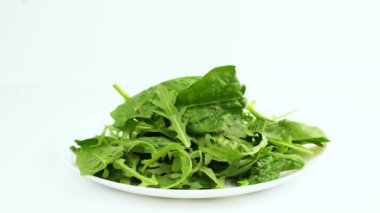 Beyaz arka planda izole edilmiş bir kasede marul yaprakları. Salata için taze roka yaprakları, marul yaprakları ve ıspanak yapraklarını karıştır..