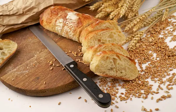 Slicing French Baguette On Slice For Bruschetta. Cutting Bread On Kitchen. Making Morning Breakfast. Fresh Bread On Table. Cutting French Baguette.