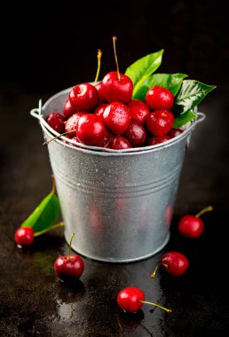 Kirazlı yaz geçmişi. Masanın üzerinde siyah yapraklar olan çok sayıda kiraz.