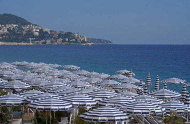 Nice 'te güneşli şezlonglar ve şemsiyelerle kumsal manzarası. Sahil ve Gezinti Güvertesi, Anglais neredeyse tüm yıl boyunca meşguldür..