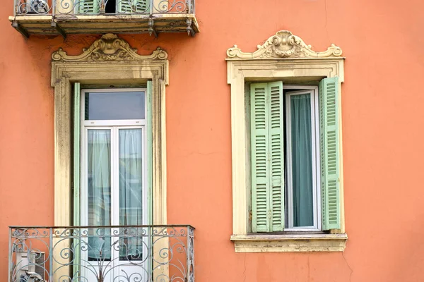 Beautiful French windows. Window frames with wooden shutters. Windows of a private house with flower pots and wooden shutters