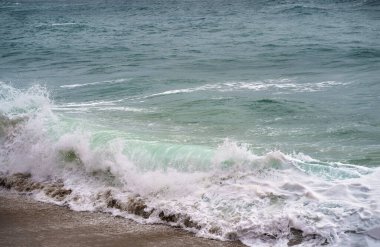 Deniz mevsimi değil, fırtınalı, kötü hava. Bir deniz dalgası beyaz köpükle kırılır ve dünyanın yüzeyine vurur, kumlu plaja.