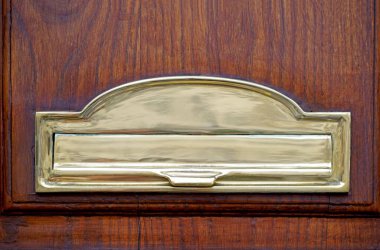 Kapıda posta kutusu var. Posta kutusunda altın posta kutusu, mektupları ve gazeteleri olan ahşap bir kapı..