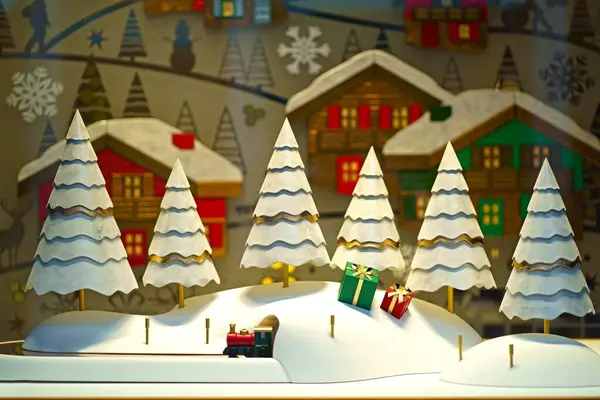 ペーパー雪の木と包まれたギフトボックスを特徴とするウィンドウディスプレイは 魅力的な冬の不思議な光景を作り出します ストック画像