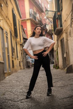 Moda modeli, Napoli 'nin tarihi merkezinde kendine güvenen bir şekilde poz veriyor. Güzel eski mimariye karşı modaya uygun kıyafetleri sergiliyor.