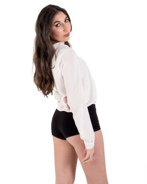 Uzun kahverengi saçlı, beyaz tişörtlü, siyah şortlu, arkasını dönüp arkasını kollayan çekici bir genç kadın.