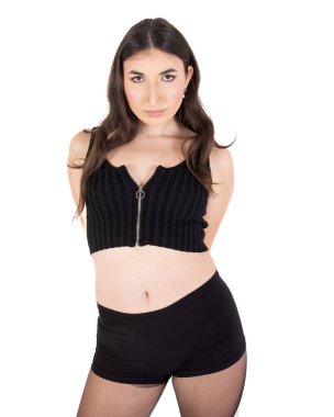 Siyah bluz, şort ve tayt giyen, kendine güveni ve tarzı olan genç bir kadının stüdyo fotoğrafı.