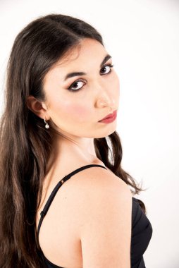 Uzun kahverengi saçlı, siyah elbiseli ve başını çeviren genç bir kadının stüdyo portresi.