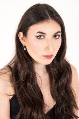 Uzun, dalgalı kahverengi saçları ve zarif makyajı olan güzel bir esmer modelin stüdyo portresi.