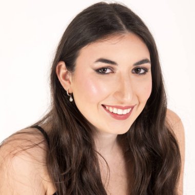 Uzun kahverengi saçlı, gülümseyen ve mükemmel beyaz dişlerini gösteren neşeli bir Latin kadının portresi.