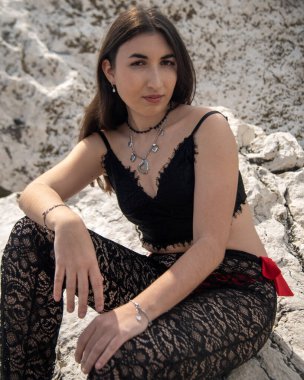 Siyah dantelli elbise giyen ve güneşli bir günde beyaz kayalarda poz veren bir manken.