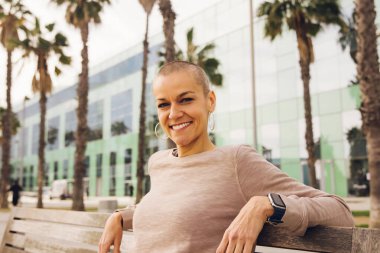 Bankta oturmuş gülümseyen mutlu kel kadın. Yüksek kalite fotoğraf