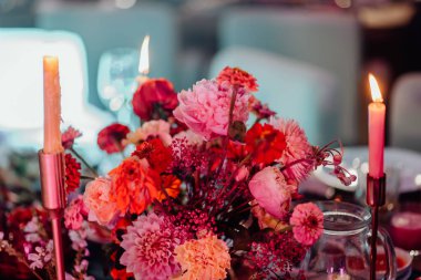 İki kişilik romantik bir akşam. Çatal bıçakla servis edilen ve üzerinde yanan mumlar bulunan taze çiçeklerle süslenmiş bir festival masası..