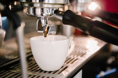 Bir kahve makinesinin boynuzunun altında beyaz bir fincan duruyor. Kahve. Barista kahve hazırlıyor.