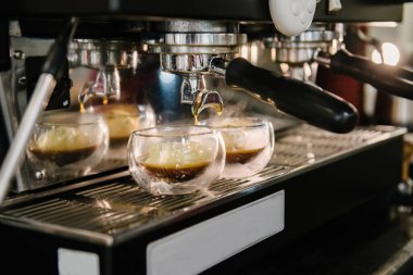 Kahve makinesi. Köpüklü kahve tutacaktan cam bardaklara dökülür. Dondurma kepçeleri bardakta. Buhar geliyor.