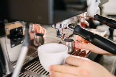 Kahveci Holden kahve makinesinin altına beyaz bir bardak koyar. Kahve yapacağım.