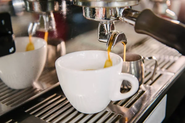 Stock image In the white cup that is in the coffee machine, fresh coffee with foam flows out of the holder