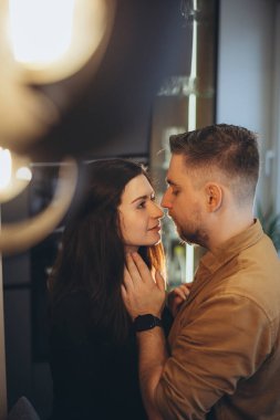 Gülümseyen bir adamın yüzü. Adamın şık bir sakalı var. Kız adama baktı ve kollarını erkeğin boynuna doladı..