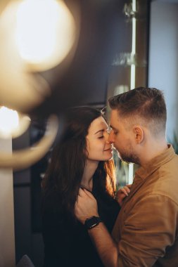 Gülümseyen bir adamın yüzü. Adamın şık bir sakalı var. Kız adama baktı ve kollarını erkeğin boynuna doladı..