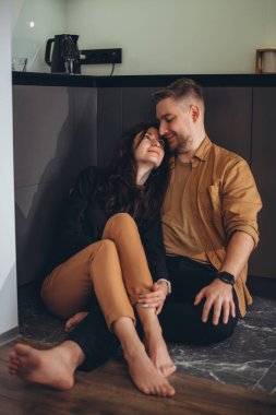 Genç bir çift mutfakta yalınayak oturuyor. Kız, gülümseyerek, bacaklarını adamın üzerine attı ve kendini onun gözlerine bastırdı. Adam kıza bakar ve gülümser.