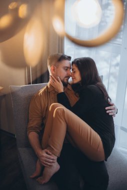 Kız, erkeğin kollarına sarılmış oturuyor. Adam nazikçe kızı tutuyor ve gözlerinin içine bakıp gülümsüyor. Birbirine aşık bir çift. Ön planda bulanıklık. Parılda