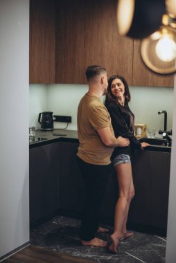 Genç bir çift mutfakta duruyor. Adam kızın arkasından sinsice yaklaşıp eliyle beline dokunuyor. Kız adama döndü ve gülümsedi.