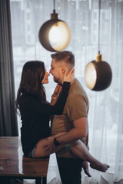 Kız, bacakları adamın boynuna dolanmış bir şekilde masaya oturur ve onu boynundan tutar. Birbirlerine bakıyorlar. Vurgularla bulanık arkaplan ve arkaplan