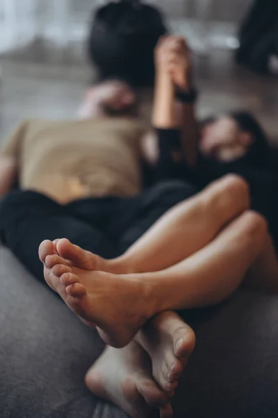 Girl and guy at home. The couple lies on the floor with their legs crossed together. Couple holding hands. Only the legs of the guy and the girl are in focus. Blurred background.
