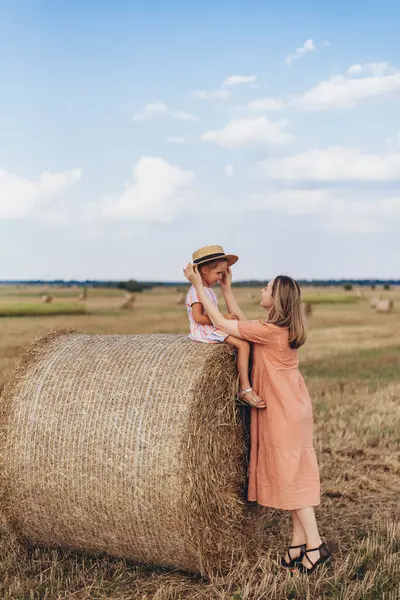 하늘을 밀밭에서 엄마와 베일에 앉아있다 엄마는 그녀의 모자를 넣습니다 스톡 이미지