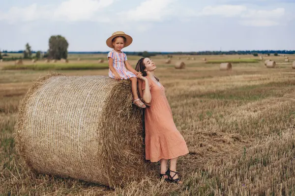 하늘을 밀밭에서 엄마와 베일에 앉아있다 엄마는 베일에 기대어 그녀의 감았습니다 스톡 이미지