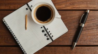 Ofis masası. Laptop, not defteri, kahve, ofis malzemeleri ve beyaz ahşap masadaki yeşil yapraklarla estetik çalışma alanı. Merkez ofis, asgari bohem tarzı, üst görünüm.