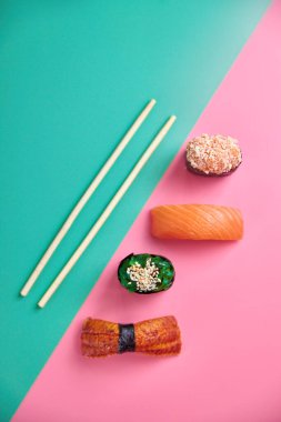 Nigiri, rulo ve sashimi 'den oluşan canlı bir suşi çeşidi. Koyu bir levhada güzelce yerleştirilmiş. Canlı renkler ve dokular deniz ürünlerinin çeşitliliğini ve tazeliğini vurgular..