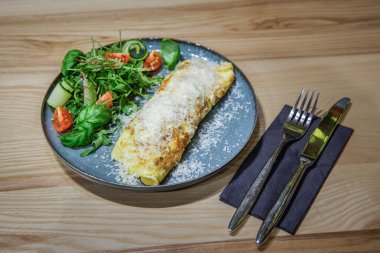 Gri masadaki tavada taze ıspanaklı omlet ve domates salatası. Kahvaltı hazır..