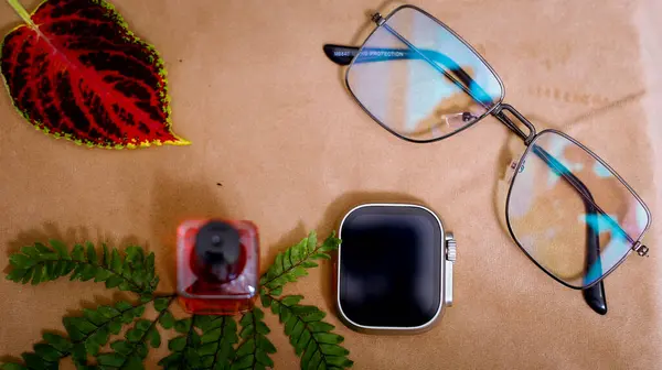 Şık akıllı saat, tırnak cilası ve güneş gözlüğü. Masa Brown arka planında. Işık Yansıması